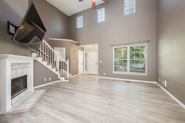 12655 S Clinton St, Olathe, KS 66061 - unfurnished living room featuring stairs, plenty of natural light, a ceiling fan, a towering ceiling, and wood finished floors