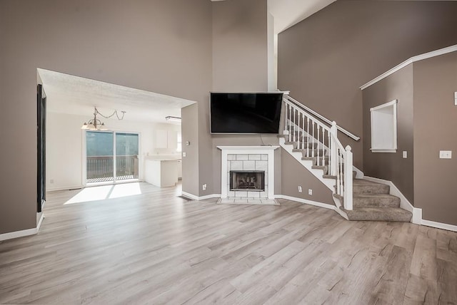 12655 S Clinton St, Olathe, KS 66061 - unfurnished living room with stairs, wood finished floors, a towering ceiling, baseboards, and a tile fireplace