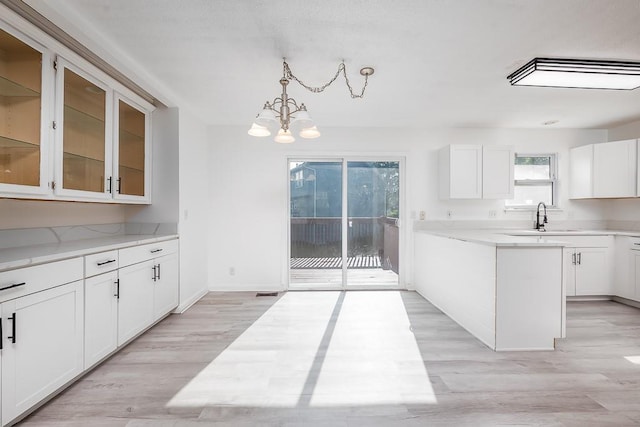 12655 S Clinton St, Olathe, KS 66061 - kitchen featuring a sink, a chandelier, light countertops, glass insert cabinets, and white cabinetry