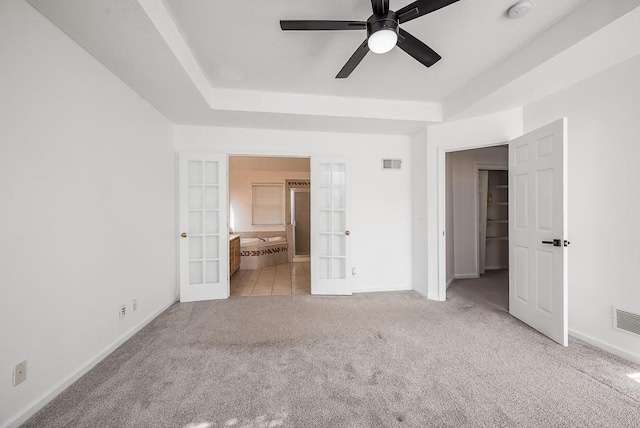 12655 S Clinton St, Olathe, KS 66061 - unfurnished bedroom with french doors, carpet, baseboards, a tray ceiling, and ensuite bath