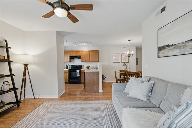 5610 NE 80th Ter Unit 1D, Kansas City, MO 64119 - living area featuring light wood-style flooring, a ceiling fan, a chandelier, rail lighting, and baseboards