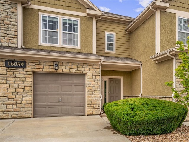 16059 Fontana St Unit 204, Overland Park, KS 66085 - property entrance with stone siding, stucco siding, an attached garage, and driveway