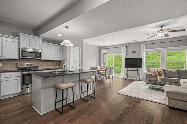 16059 Fontana St Unit 204, Overland Park, KS 66085 - kitchen featuring stainless steel appliances, a sink, open floor plan, dark countertops, and a kitchen breakfast bar