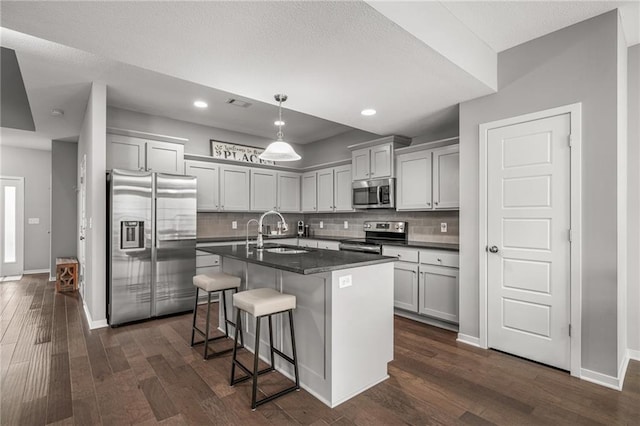 16059 Fontana St Unit 204, Overland Park, KS 66085 - kitchen featuring appliances with stainless steel finishes, a sink, dark countertops, dark wood-type flooring, and decorative backsplash
