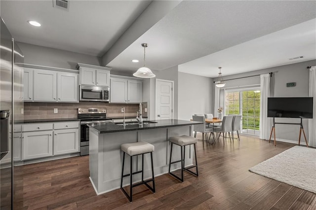 16059 Fontana St Unit 204, Overland Park, KS 66085 - kitchen with stainless steel appliances, a sink, dark countertops, backsplash, and a kitchen breakfast bar