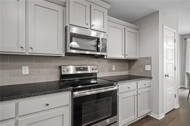 16059 Fontana St Unit 204, Overland Park, KS 66085 - kitchen with appliances with stainless steel finishes, dark wood-style floors, decorative backsplash, baseboards, and a textured ceiling