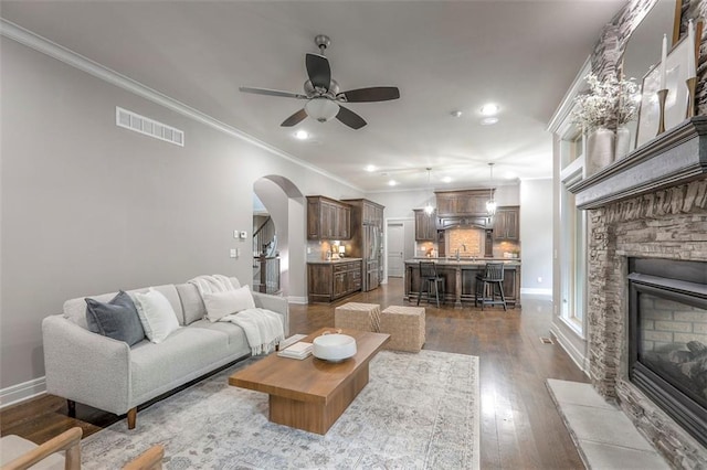 14095 NW 60th Ct, Parkville, MO 64152 - living room with crown molding, a ceiling fan, recessed lighting, a stone fireplace, and arched walkways