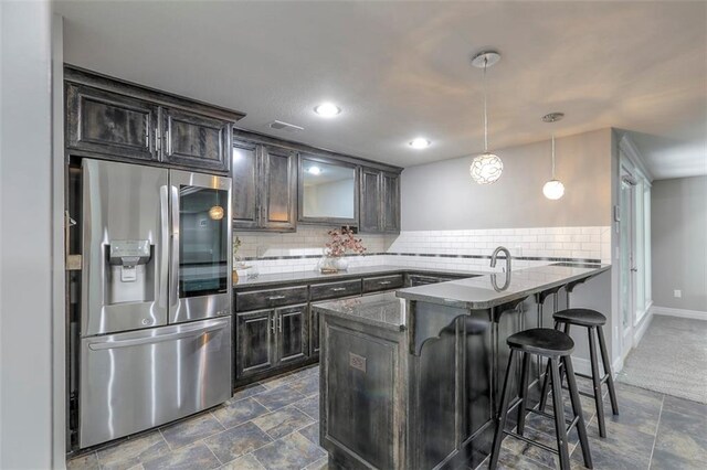 14095 NW 60th Ct, Parkville, MO 64152 - kitchen featuring stainless steel fridge with ice dispenser, a peninsula, tasteful backsplash, a breakfast bar, and dark stone finish floors