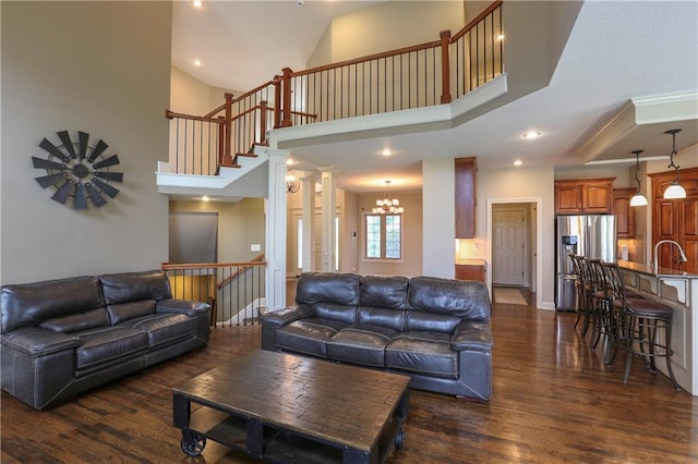 16488 S Summertree Ln, Olathe, KS 66062 - living area featuring dark wood finished floors, ornate columns, a towering ceiling, a chandelier, and recessed lighting