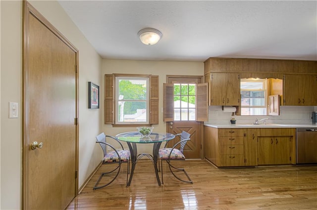 5037 Spring Ave, Kansas City, MO 64133 - kitchen with stainless steel dishwasher, light countertops, brown cabinets, and light wood-style flooring