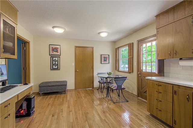 5037 Spring Ave, Kansas City, MO 64133 - kitchen with light countertops, light wood finished floors, baseboards, tasteful backsplash, and a textured ceiling