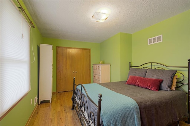 5037 Spring Ave, Kansas City, MO 64133 - bedroom featuring wood finished floors, a closet, a textured ceiling, and baseboards