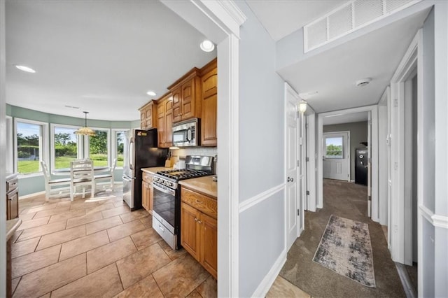 2640 Union Rd, Lawrence, KS 66044 - kitchen featuring appliances with stainless steel finishes, light countertops, brown cabinets, recessed lighting, and hanging light fixtures