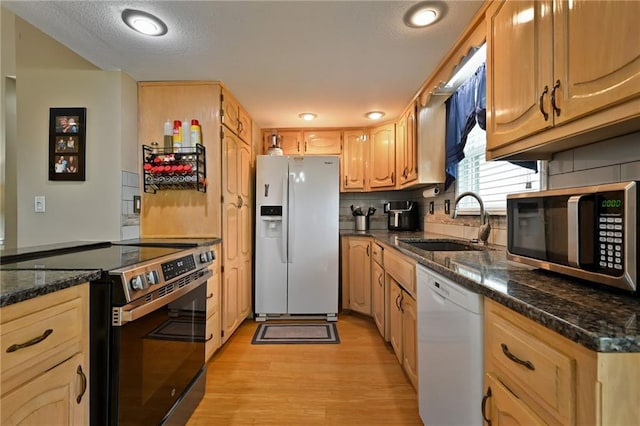 404 NE 96th Ter, Kansas City, MO 64155 - kitchen featuring stainless steel appliances, a sink, light wood-style flooring, tasteful backsplash, and dark stone countertops