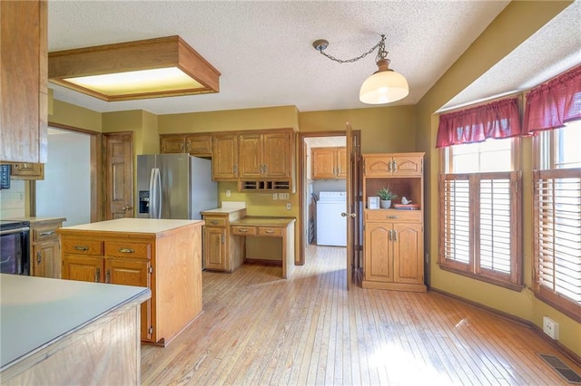 324 N Persimmon Dr, Olathe, KS 66061 - kitchen featuring stainless steel fridge, washer / dryer, light countertops, light wood-style flooring, and a textured ceiling