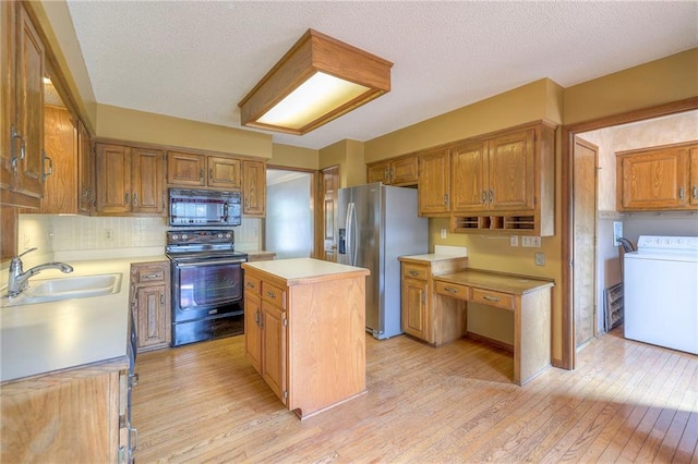 324 N Persimmon Dr, Olathe, KS 66061 - kitchen featuring black appliances, washer / dryer, light countertops, light wood-style floors, and a center island