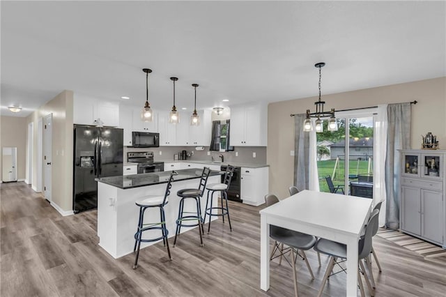 2604 S 16th Ter, Leavenworth, KS 66048 - kitchen with black appliances, a center island, white cabinetry, a kitchen bar, and a chandelier