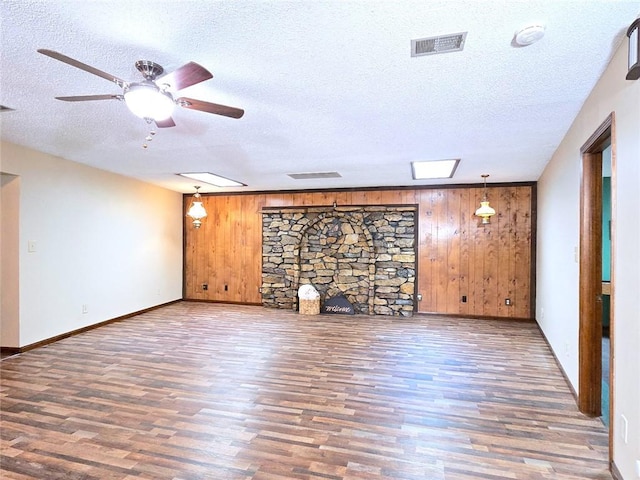 2101 Hillview Rd, Liberty, MO 64068 - unfurnished living room with wood finished floors, wooden walls, a ceiling fan, and a textured ceiling