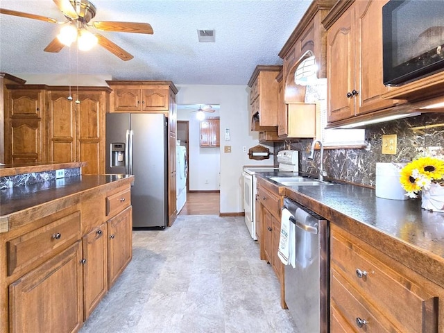 2101 Hillview Rd, Liberty, MO 64068 - kitchen featuring stainless steel appliances, a ceiling fan, dark countertops, brown cabinetry, and tasteful backsplash