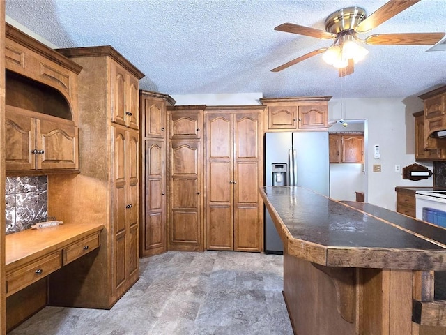 2101 Hillview Rd, Liberty, MO 64068 - kitchen featuring stainless steel fridge with ice dispenser, brown cabinets, a ceiling fan, dark countertops, and a textured ceiling