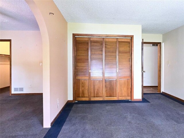 2101 Hillview Rd, Liberty, MO 64068 - unfurnished bedroom with arched walkways, a closet, carpet floors, and a textured ceiling