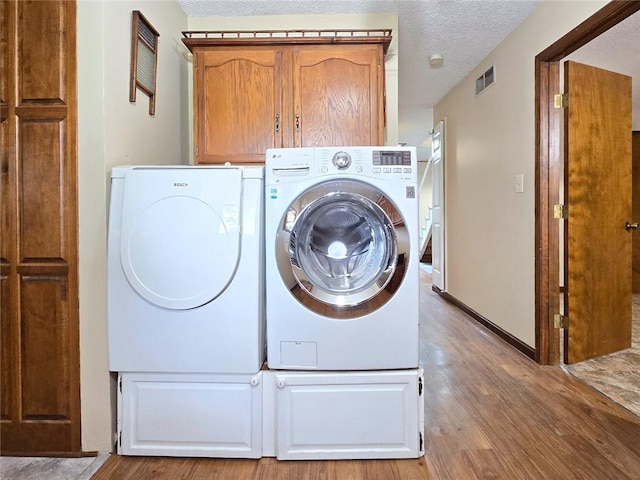 2101 Hillview Rd, Liberty, MO 64068 - laundry area with washer and clothes dryer, wood finished floors, cabinet space, and a textured ceiling