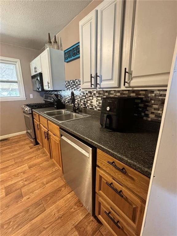 32592 SE 500th Rd, Kincaid, KS 66039 - kitchen featuring stainless steel appliances, dark countertops, light wood-style floors, decorative backsplash, and a textured ceiling