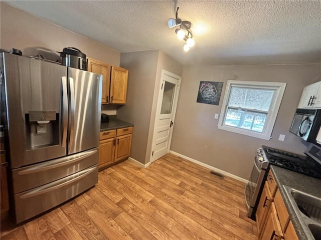 32592 SE 500th Rd, Kincaid, KS 66039 - kitchen featuring stainless steel appliances, dark countertops, a textured ceiling, light wood finished floors, and brown cabinetry
