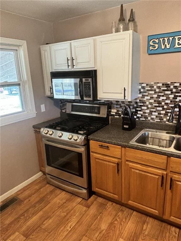 32592 SE 500th Rd, Kincaid, KS 66039 - kitchen with appliances with stainless steel finishes, dark countertops, white cabinets, and light wood-type flooring