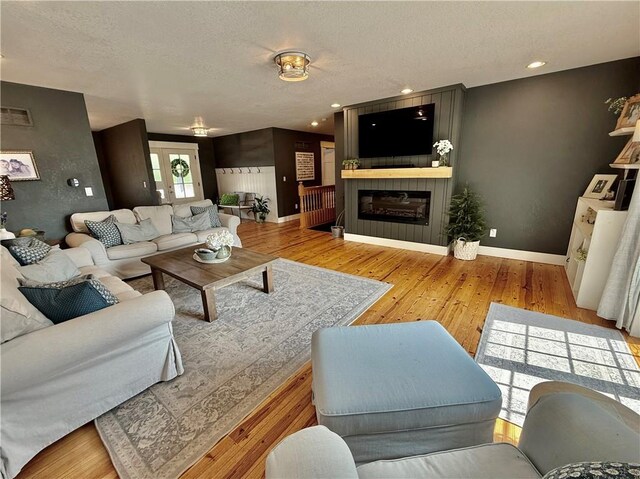 226 James Ave, Maryville, MO 64468 - living area featuring wood finished floors, a large fireplace, a textured ceiling, baseboards, and recessed lighting