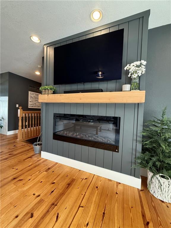 226 James Ave, Maryville, MO 64468 - detailed view of wood finished floors, a glass covered fireplace, a textured ceiling, baseboards, and recessed lighting