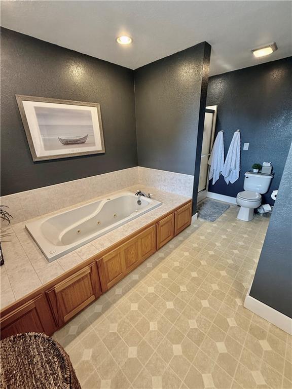 226 James Ave, Maryville, MO 64468 - full bath featuring toilet, a tub with jets, a stall shower, and baseboards