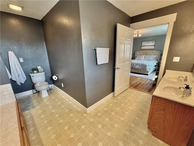 226 James Ave, Maryville, MO 64468 - full bathroom featuring a textured wall, double vanity, toilet, connected bathroom, and tile patterned floors