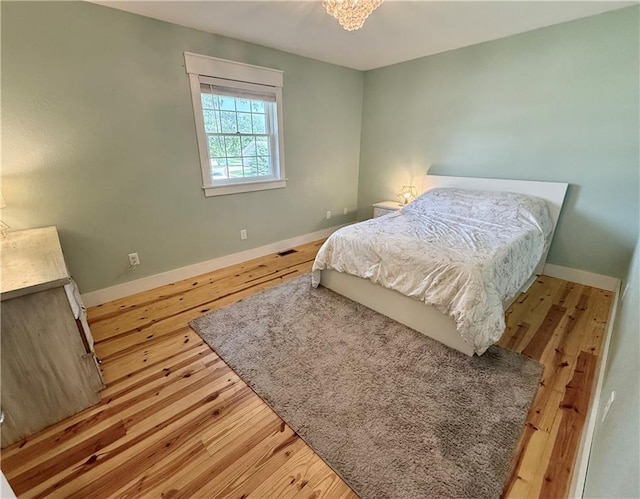 226 James Ave, Maryville, MO 64468 - bedroom with wood finished floors, baseboards, and a chandelier