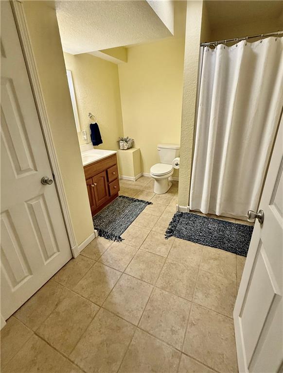 226 James Ave, Maryville, MO 64468 - full bathroom with vanity, toilet, tile patterned flooring, a shower with curtain, and a textured ceiling