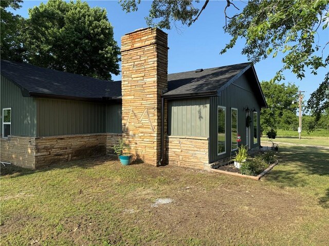 4004 Texaco Rd, Cushing, OK 74023 - view of side of home with roof with shingles, a yard, and a chimney