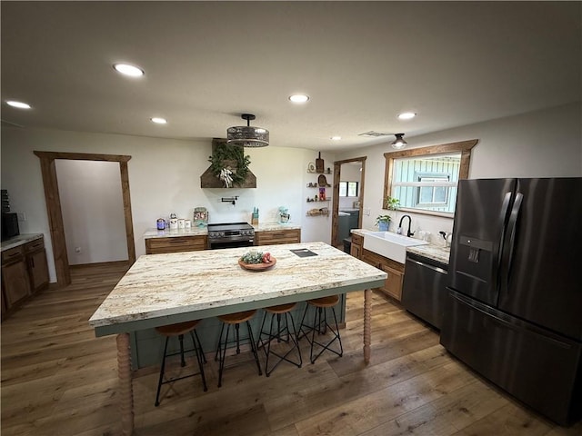 4004 Texaco Rd, Cushing, OK 74023 - kitchen featuring stainless steel appliances, a sink, a kitchen breakfast bar, recessed lighting, and wood finished floors