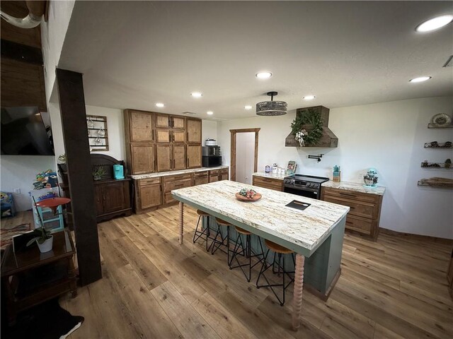 4004 Texaco Rd, Cushing, OK 74023 - kitchen with custom range hood, brown cabinets, stainless steel range with electric cooktop, recessed lighting, and light wood-style floors