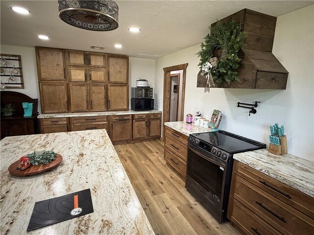 4004 Texaco Rd, Cushing, OK 74023 - kitchen featuring black appliances, light wood finished floors, recessed lighting, brown cabinetry, and light stone countertops