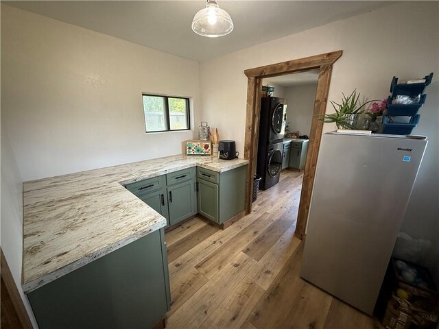 4004 Texaco Rd, Cushing, OK 74023 - kitchen featuring freestanding refrigerator, stacked washer / drying machine, light wood-style floors, green cabinets, and hanging light fixtures
