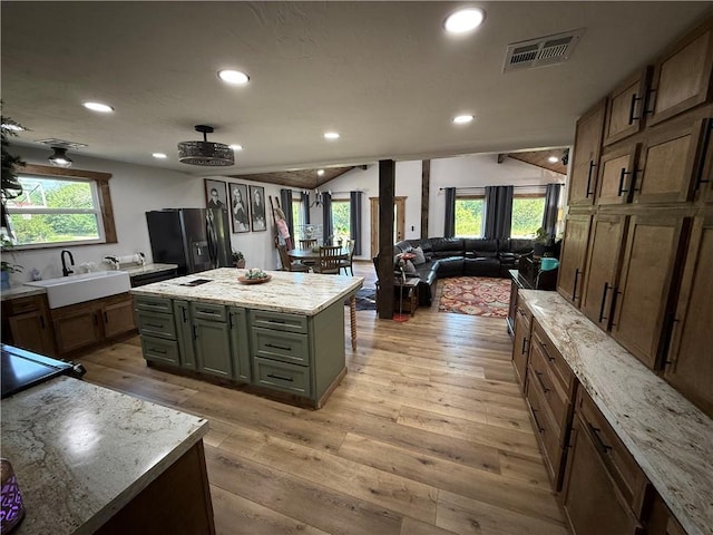 4004 Texaco Rd, Cushing, OK 74023 - kitchen featuring black fridge with ice dispenser, a sink, light wood-type flooring, vaulted ceiling, and open floor plan