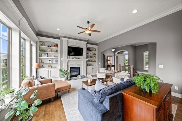 17208 W 198th St, Spring Hill, KS 66083 - living area featuring healthy amount of natural light, ornamental molding, arched walkways, wood finished floors, and a ceiling fan