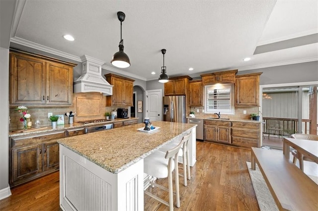 17208 W 198th St, Spring Hill, KS 66083 - kitchen featuring stainless steel appliances, premium range hood, arched walkways, brown cabinetry, and recessed lighting