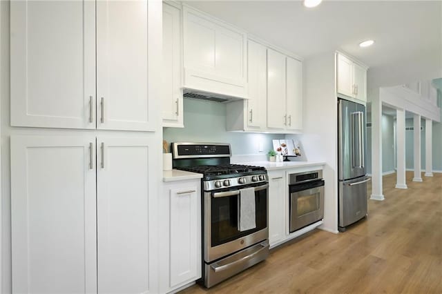 10775 Larsen St, Overland Park, KS 66210 - kitchen with stainless steel appliances, light countertops, white cabinets, light wood-style floors, and recessed lighting