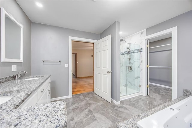 3931 Main St, Parsons, KS 67357 - full bathroom featuring a marble finish shower, double vanity, baseboards, a tub with jets, and a spacious closet