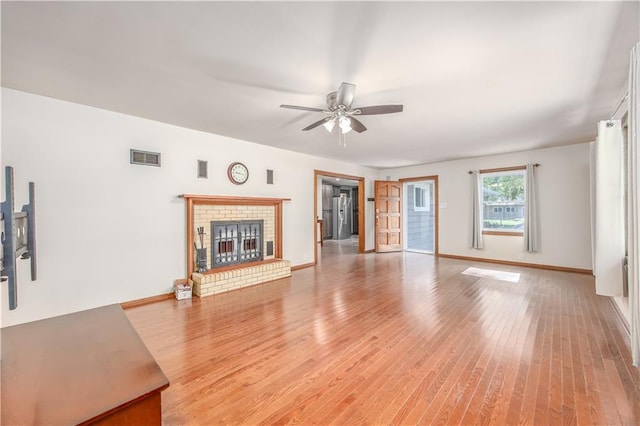 3931 Main St, Parsons, KS 67357 - unfurnished living room with a ceiling fan, light wood finished floors, a brick fireplace, and baseboards