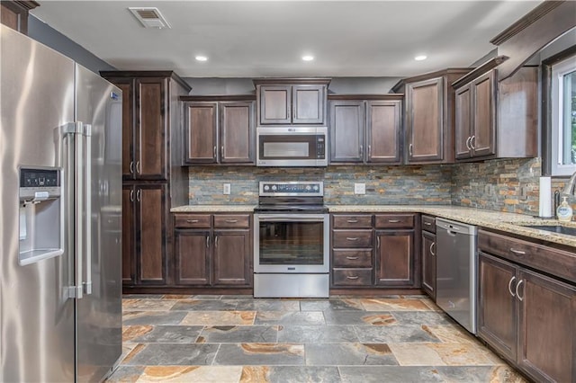 3931 Main St, Parsons, KS 67357 - kitchen featuring appliances with stainless steel finishes, dark brown cabinets, backsplash, stone finish flooring, and recessed lighting