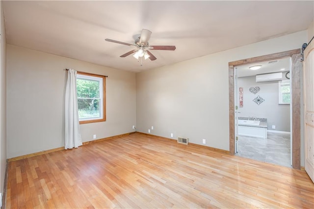 3931 Main St, Parsons, KS 67357 - spare room featuring a ceiling fan, an AC wall unit, light wood-style floors, and baseboards