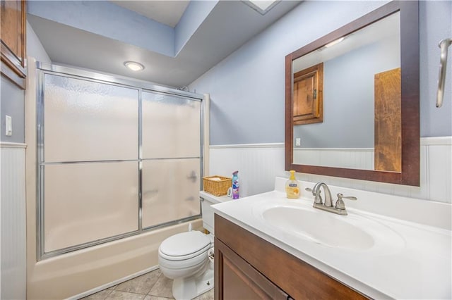 3931 Main St, Parsons, KS 67357 - full bath featuring wainscoting, vanity, toilet, bath / shower combo with glass door, and tile patterned floors