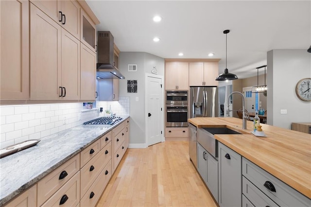 13807 W 47th Ter, Shawnee, KS 66216 - kitchen with wall chimney range hood, stainless steel appliances, light wood-type flooring, a sink, and butcher block countertops